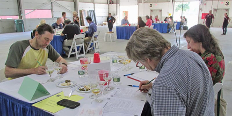 Men and woman at a table writing on judge sheet at wine contest