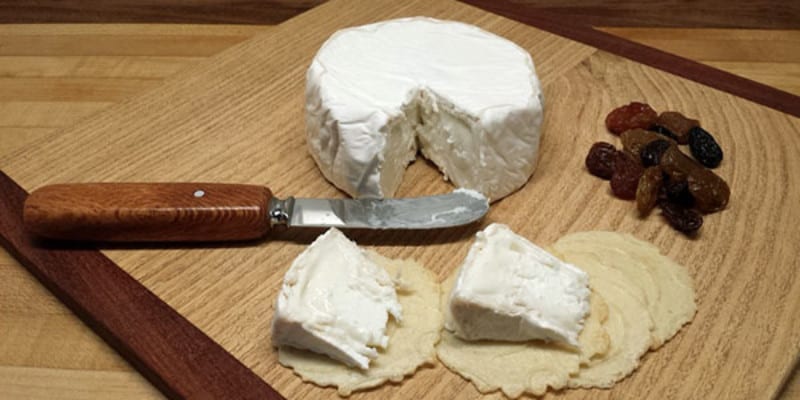 Block of cheese with knife and cut out pieces next to it