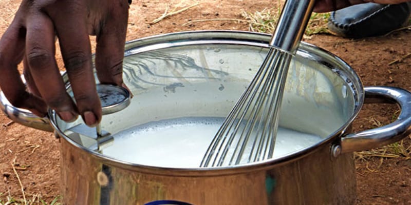 Mixing milk with a whisk in a metal pot