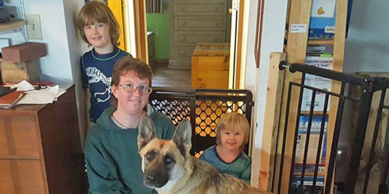 Three kids with their German Shepard in a house