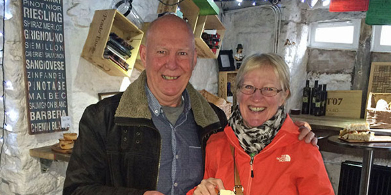 A man and woman smiling with a piece of cheese.