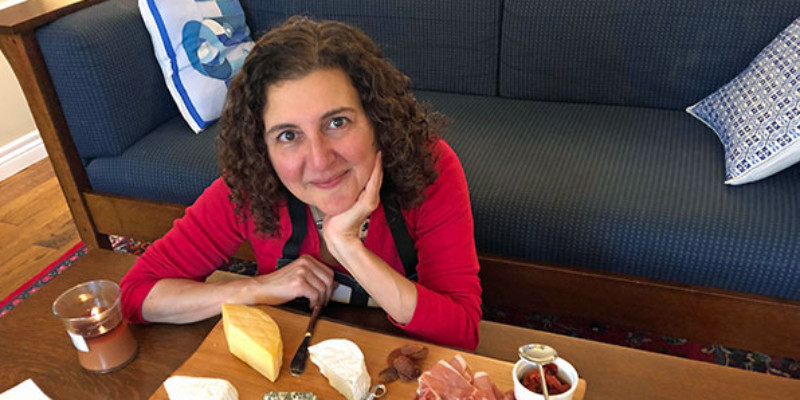 A woman smiling with a cheese charcuterie board