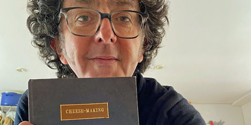 A woman holding a cheesemaking book